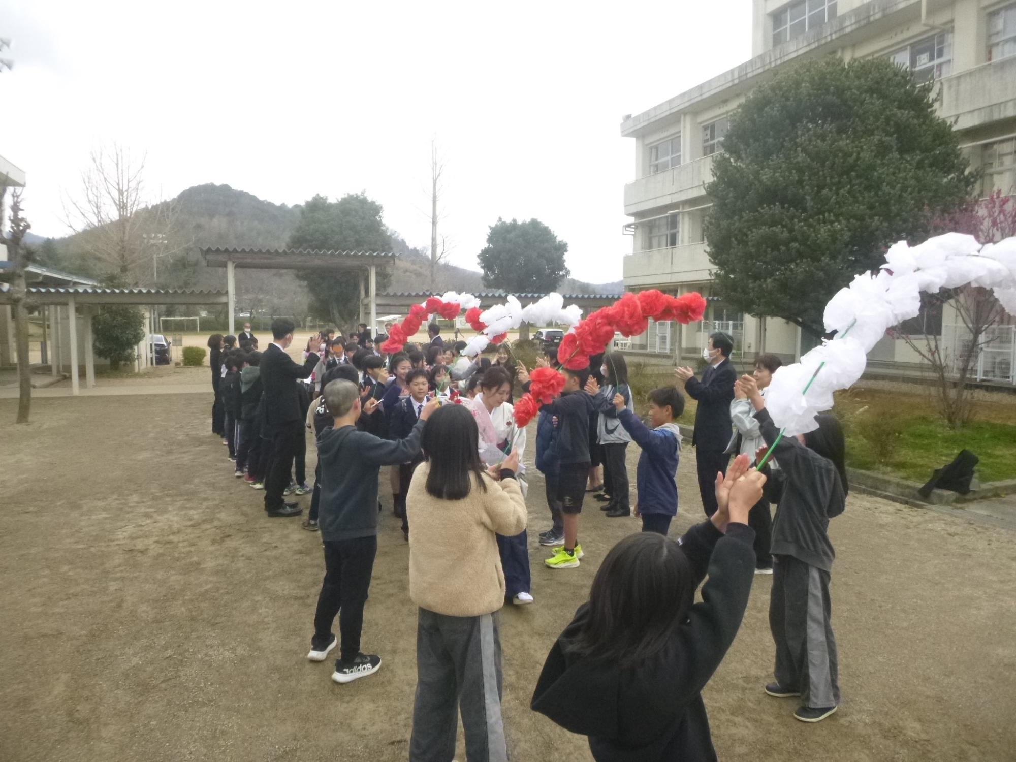 5年生が持つ花のアーチをくぐって