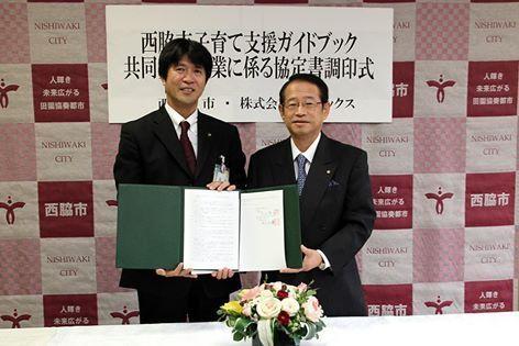協定調印書を持ち記念撮影する株式会社サイネックスの村田吉優代表取締役社長（右）と片山市長