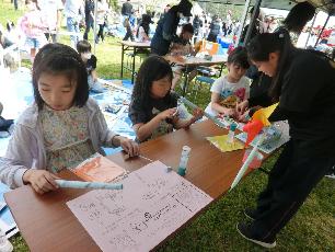 高校生に教えてもらって風車作りをする小学生