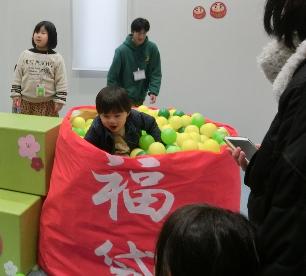 ボールの入った大きな福袋に入って遊ぶ子ども