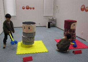 大きなだるま落としで遊ぶ子どもたち