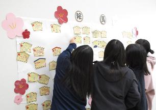 自分の書いた絵馬を貼り付ける中学生たち
