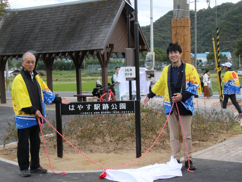 はやす駅跡公園の案内板を披露する片山市長と齋藤日野地区代表区長