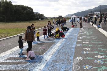 日野北バイパス開通前のイベントで道路に絵を描く親子連れら