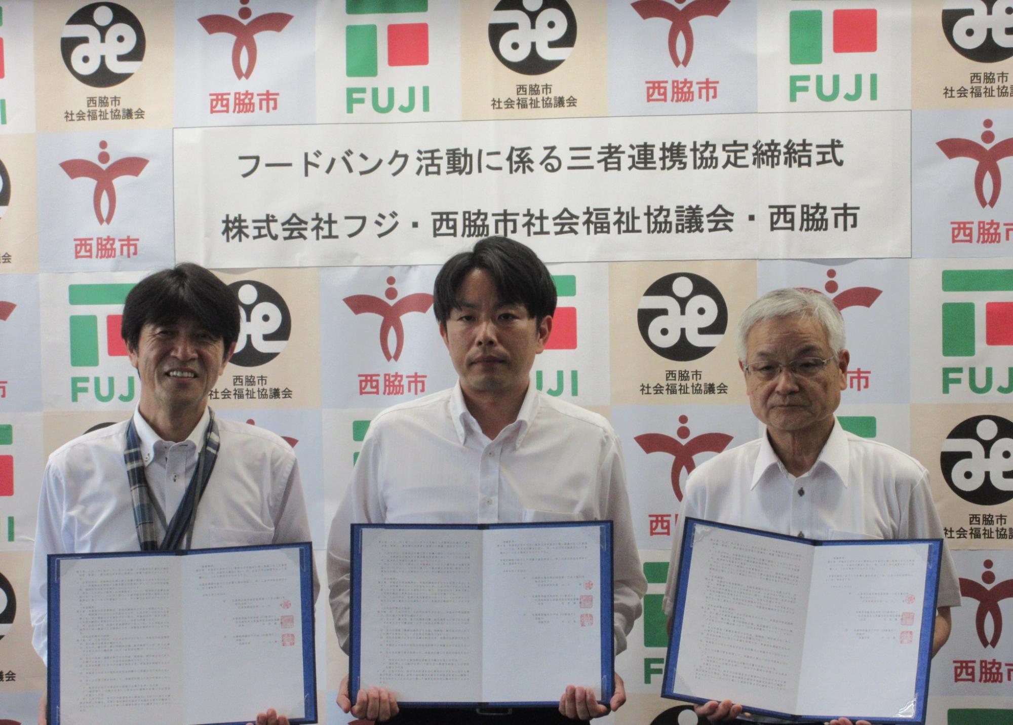 協定書を披露する片山市長（左側）と株式会社フジ　山本近畿営業本部長（中央）並びに西脇市社会福祉協議会　牛居会長（右側）