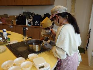 一緒にぜんざいの配膳をする高校生と小学生キッチンスタッフ