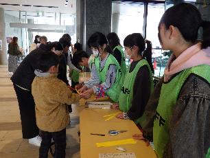 受付係で参加者にリストバンドを巻いている小学生