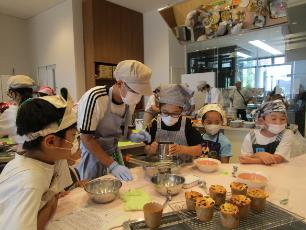 工業高校家庭部の生徒と一緒に調理する小学生
