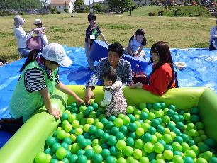 ボールプールで遊ぶ幼児と小学生を見守る父母