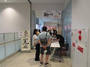 お面屋さんに並ぶ親子