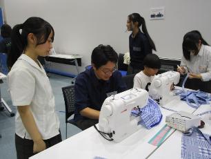 高校生の指導のもとミシンを使う父親