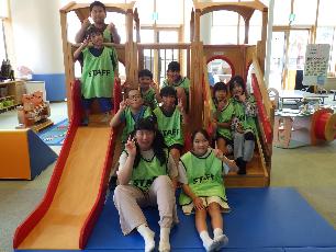 木製の滑り台前で記念撮影する職員体験の小学生